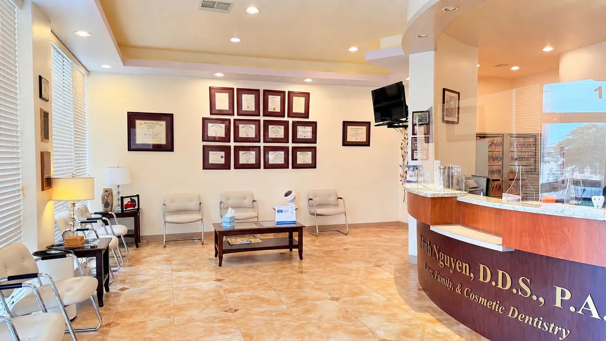 SoftDental reception area with credential wall showing Dr. Nguyen's framed dental and continuing education certificates