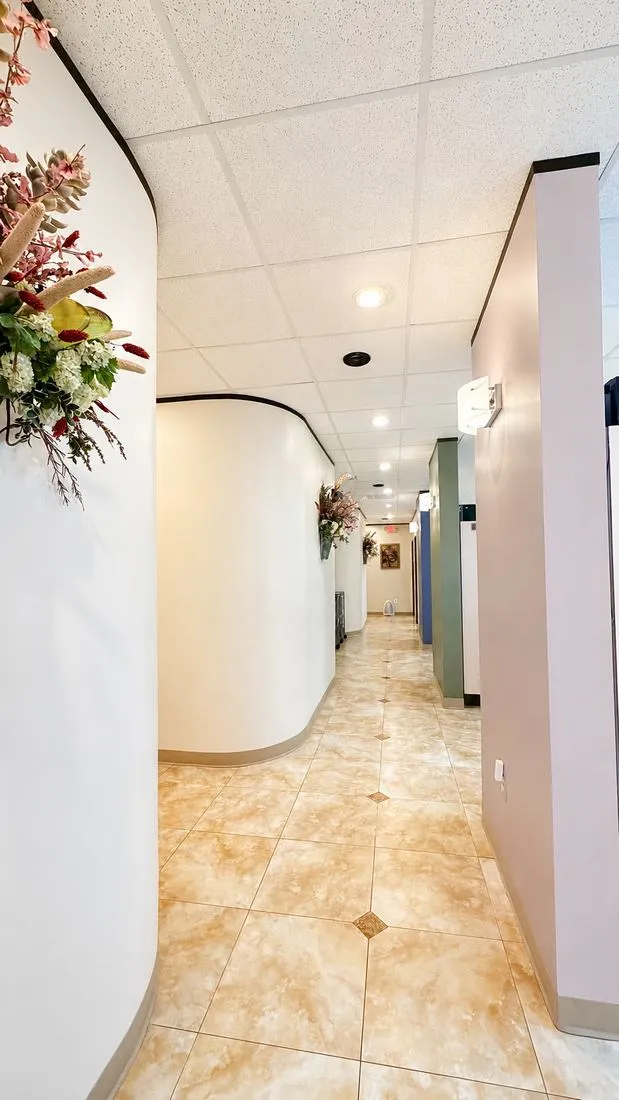 SoftDental hallway leading to treatment rooms, featuring curved walls and warm floral accents